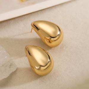 Polished gold-plated teardrop earrings with a glossy finish on a textured surface