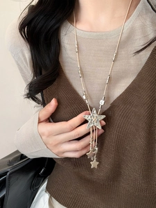 Detail of star pendant on bohemian leather cord necklace worn with autumn knitwear