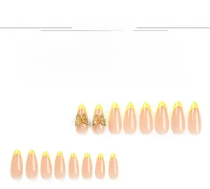 Detail view of yellow French tip press-on nails with 3D golden butterfly rhinestones