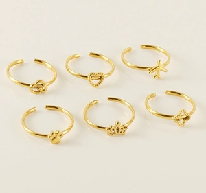 Detailed close-up of six gold adjustable rings with heart, crown, and airplane motifs