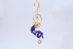 Detailed blue enamel dragon keychain with small golden coin charm on white background