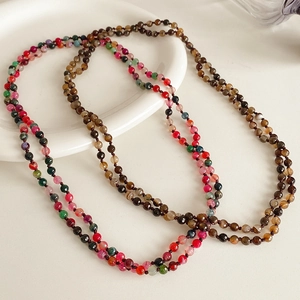 Macro shot of colorful natural stone beads on a white plate for a bohemian necklace