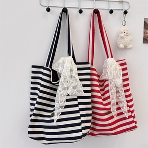 Detail of striped canvas tote with elegant lace bow charm and metallic logo plate