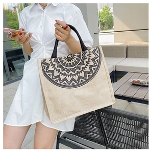 Ethnic style woven tote bag with bohemian pattern held by a model in outdoor setting