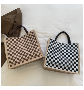 Macro view of checkered tote bags in brown and black canvas texture laid on white fabric