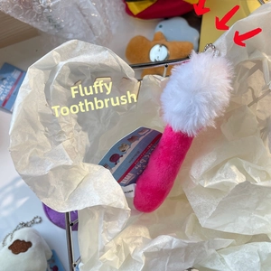 Detailed view of creative toothbrush plush keychain with pink handle and fluffy white bristles
