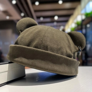 Detailed macro of dark olive green knit beanie with bear ears and metal ring accent