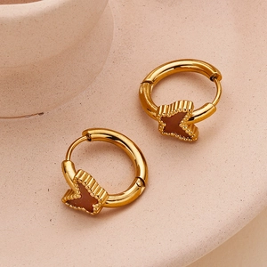 Detail showing golden butterfly hoop earrings with dark brown resin inlay on ceramic base