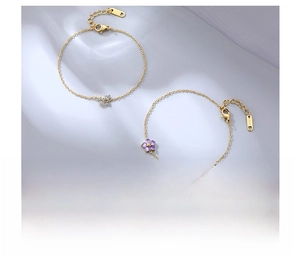 Detail of titanium steel bracelets with pink and purple flower charms in gold finish