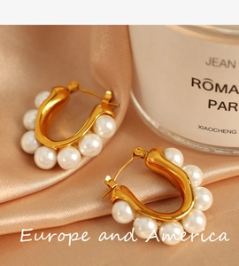 Close-up of gold U-shaped earrings with pearls against elegant silk background