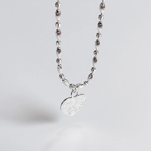 Macro detail of 925 sterling silver heart pendant with shimmering frosted texture
