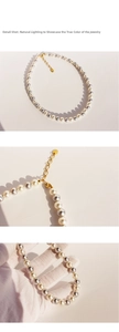 Detail of grey and white pearl necklace with gold clasp under natural lighting