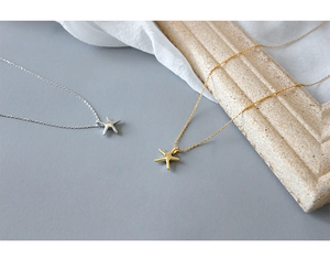Detail view of silver and gold starfish pendants on elegant minimalist necklaces