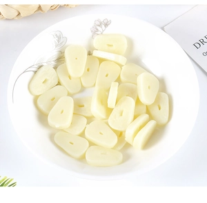 Detailed view of realistic PVC garlic slices on a white plate for miniature food DIY play