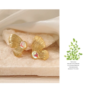 Macro view of gold butterfly earring with iridescent gemstone on stone background