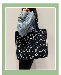 Detail of a large black canvas tote bag featuring a minimalist white cat illustration