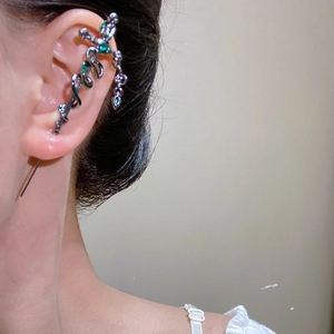 Detail of silver snake sword ear cuff with green gems and a small teardrop pendant