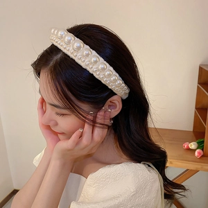 Detail of white velvet headband with pearls worn by a model in warm indoor light