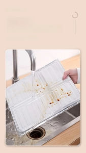 Washing the folding aluminum foil kitchen oil splash guard under a running faucet