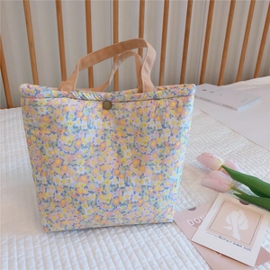 Detail of floral quilted lunch bag showing soft cotton fabric and metal snap button closure