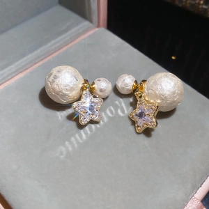 Macro view of gold star earrings with sparkling zircon and textured cotton pearls on velvet