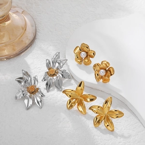 Three pairs of elegant 18k gold and silver flower earrings with pearls on white display