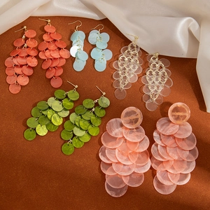 Macro shot of colorful tiered shell disk tassel earrings in coral, blue and green colors