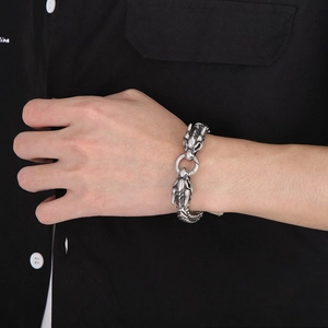 Detail of vintage silver double dragon head bracelet with textured scales on a wrist