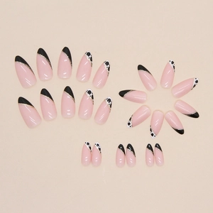 French almond press-on nails with black cow print patterns and gold glitter accents
