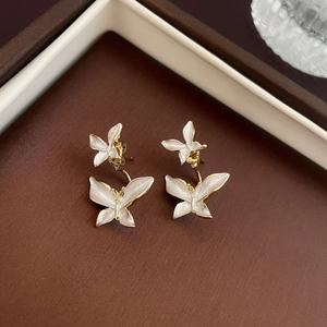 Detailed macro of gold butterfly earrings with white enamel on a jewelry box
