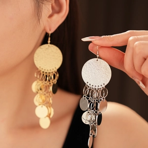 Macro shot of tiered round metal sequin fringe earrings in gold and silver finish