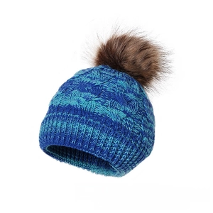 Detailed knit pattern of a blue winter beanie featuring a large brown faux fur pom pom