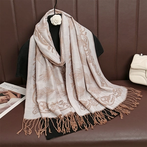 Dettaglio della sciarpa jacquard beige vintage con motivo paisley e nappe su divano