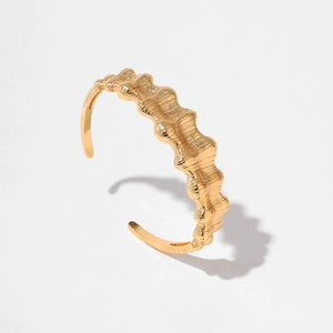 Modern gold-plated open bangle with irregular wavy texture and metal finish on white background
