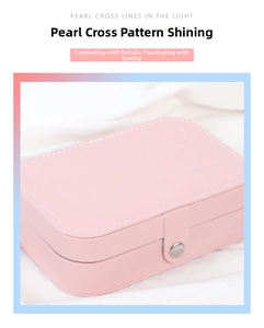 Detail of pink jewelry box featuring pearlescent cross pattern and metal snap closure