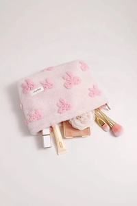 Detailed view of pink plush makeup bag with floral patterns and sturdy metal zipper
