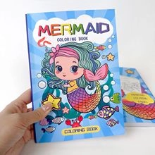 Close-up of mermaid coloring book cover and paper thickness held by hand on white surface