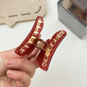Red glitter butterfly hair claw clip with gold accents shown being held for detail