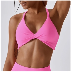Detail of twist-front hot pink yoga sports bra with halter neck and elastic fabric