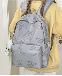 Detailed view of grey butterfly backpack with white cloud pendant on the side pocket