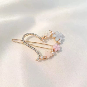 Elegant gold heart hair clip with floral accents, pearls, and rhinestones on white silk