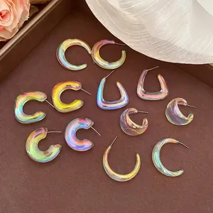 Iridescent acrylic geometric C-shaped earrings with soft rainbow metallic finish on a tray