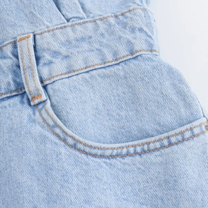 Detailed macro shot of light blue denim waistband with contrast amber stitching