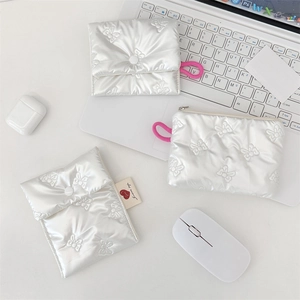 Quilted white storage pouch with bow pattern and pink elastic strap on a desk setup