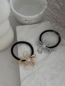 Detail of gold and silver hollow flower hair ties with pearls on an elegant stone surface