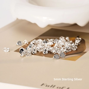 Macro shot of 5mm S925 sterling silver butterfly earring backs on a magazine page