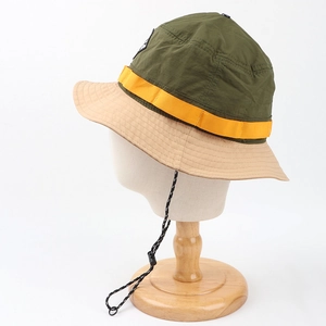 Detail of color-block sun hat featuring olive green nylon and checkered windproof strap