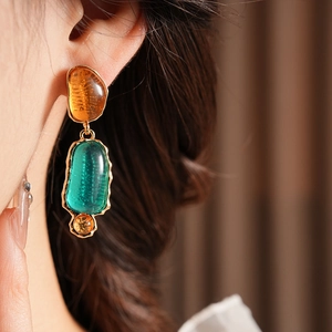 Close-up of vintage resin oval earrings with gold metal frame worn by a model