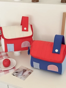 Detail view of quilted house-shaped travel bags with buttoned handles and fabric patchwork