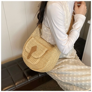 Detailed view of woven straw crossbody bag with brown leather accents and metal buckle